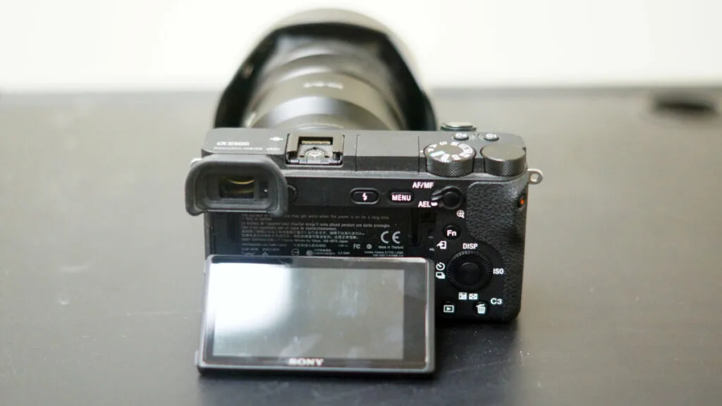 Rear view of Sony a6500 camera with tilting LCD screen extended, showing controls and viewfinder.