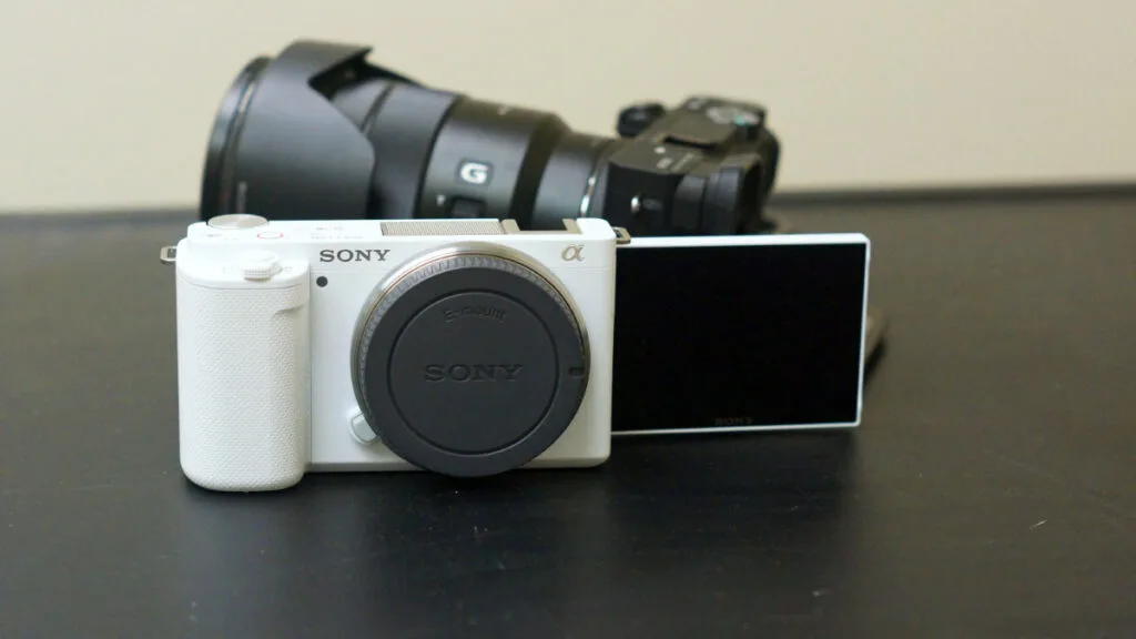 White Sony ZV-E10 camera with its flip-out LCD screen extended to the side.